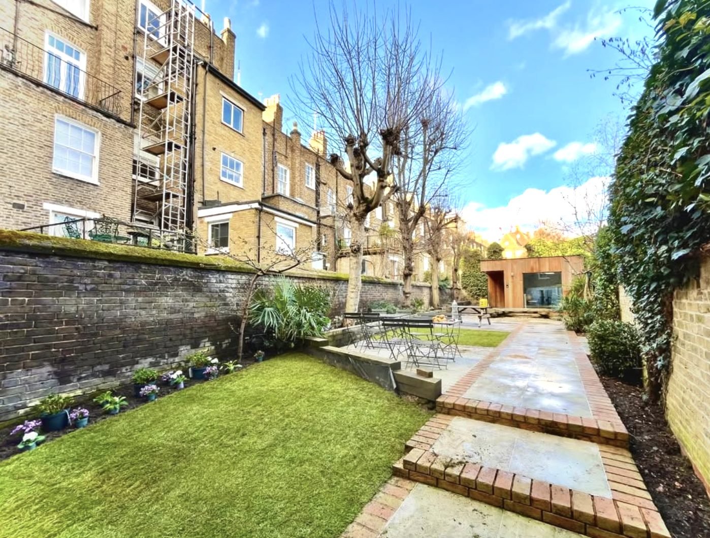 Brick-edged paving path and lawn leading to a garden room